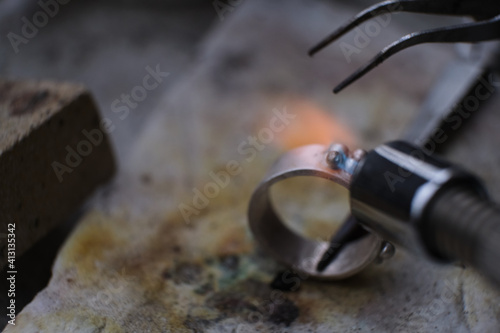 Macro shot. Craft jewelery making with professional tools. A handmade jeweler process, manufacture of jewellery. Melting metal photo