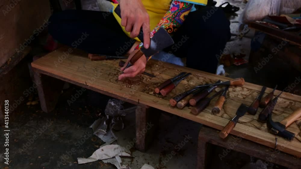Woman at San Kamphaeng handicraft village in Thailand carving a beautiful piece of a storyboard.