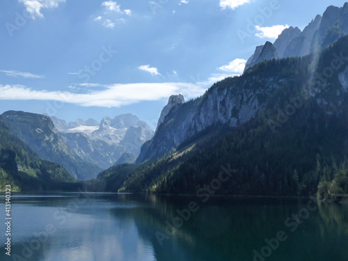 Panoramic view on Gosau lake, with Dachstein glacier in the back in Austrian Alps. The lake is surrounded by high mountains, overgrown with tall trees. Sun reflects on the surface. Serenity  and calm © Chris