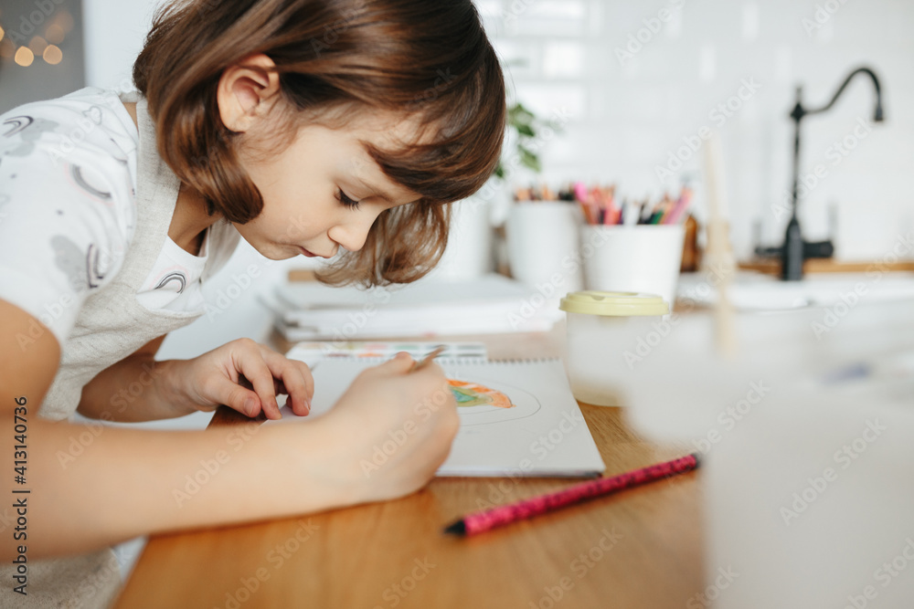 Kids painting watercolor rainbows at table at home Kids painting watercolor rainbows at table at home