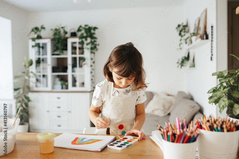 Kids painting watercolor rainbows at table at home