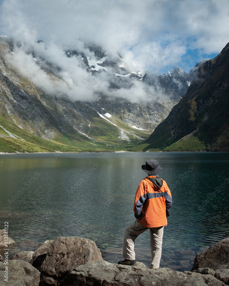 Tourist standing on the shore of Lake Marian and enjoying the views, Fiordland National Park, New Zealand. Vertical format.