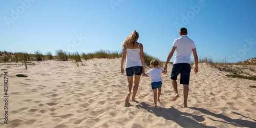 behind family father mother and daughter child back view on beach at sea walking on sand © OceanProd