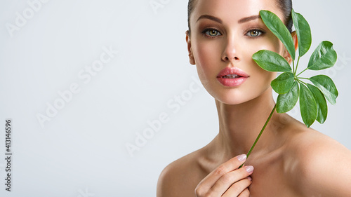 Beautiful woman with green leave near face and body.  Closeup girl's face with green leave. Skin care beauty treatments concept.