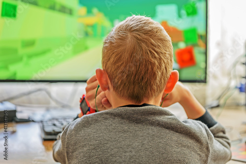 A boy with headphones is playing a computer game