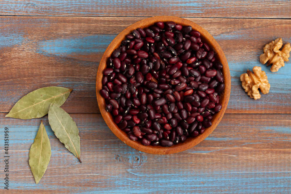 haricot beans in a wooden bowl, walnuts and laurel leaves on blue and brown wood boards haricot beans in a wooden bowl, walnuts and laurel leaves on blue and brown wood boards