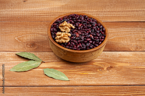 Fototapeta Naklejka Na Ścianę i Meble -  haricot beans in a wooden bowl, walnuts and laurel leaves on brown wood boards