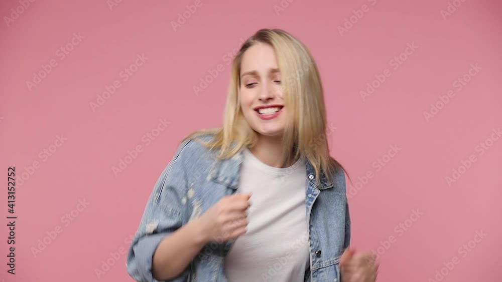 Cheerful funny blonde young woman 20s years old in white t-shirt denim jacket isolated on pastel pink background studio. People lifestyle concept. Dancing snapping fingers waving hands shaking head Cheerful funny blonde young woman 20s years old in white t-shirt denim jacket isolated on pastel pink background studio. People lifestyle concept. Dancing snapping fingers waving hands shaking head