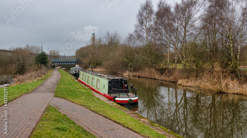 Looking down a canal with two boats moored and no people on the towpath