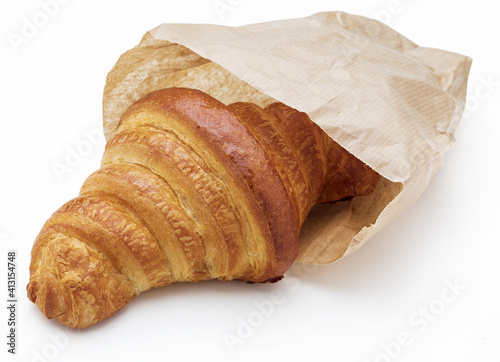 Crispy fresh butter croissant. In a paper bag. Isolated on white background.
