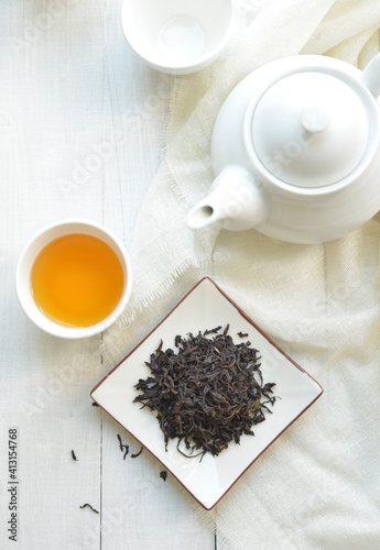 Finest quality blended tea powder. Black tea leaves and refreshing tea filled in a cup along with white tea pot. View from above.