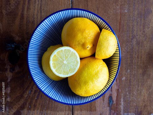 Top view of lemons in a bowl on wooden table. 