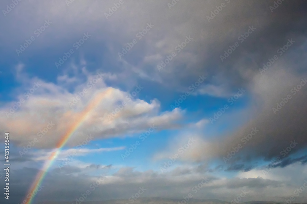 Blue cloudy sky with rainbow. Nature background.