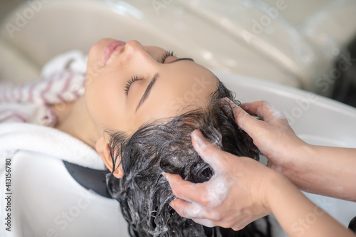 Woman feeling relaxed while hair stylist washing her hair