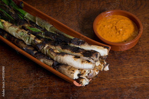 Calçots served on a tile with romesco sauce on wooden table photo