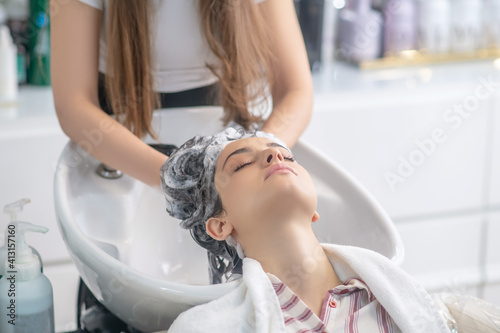 Hairdresser wahsing her customers hair with shampoo