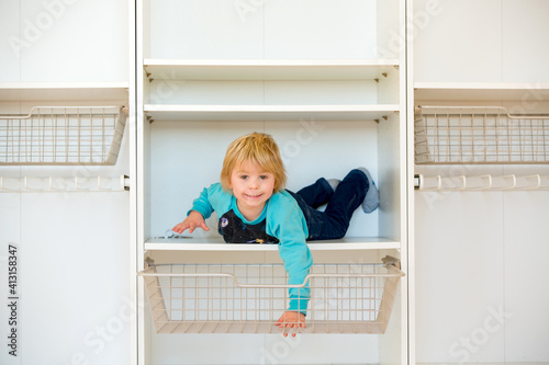 Cute child, sit in a white box in open wardrope