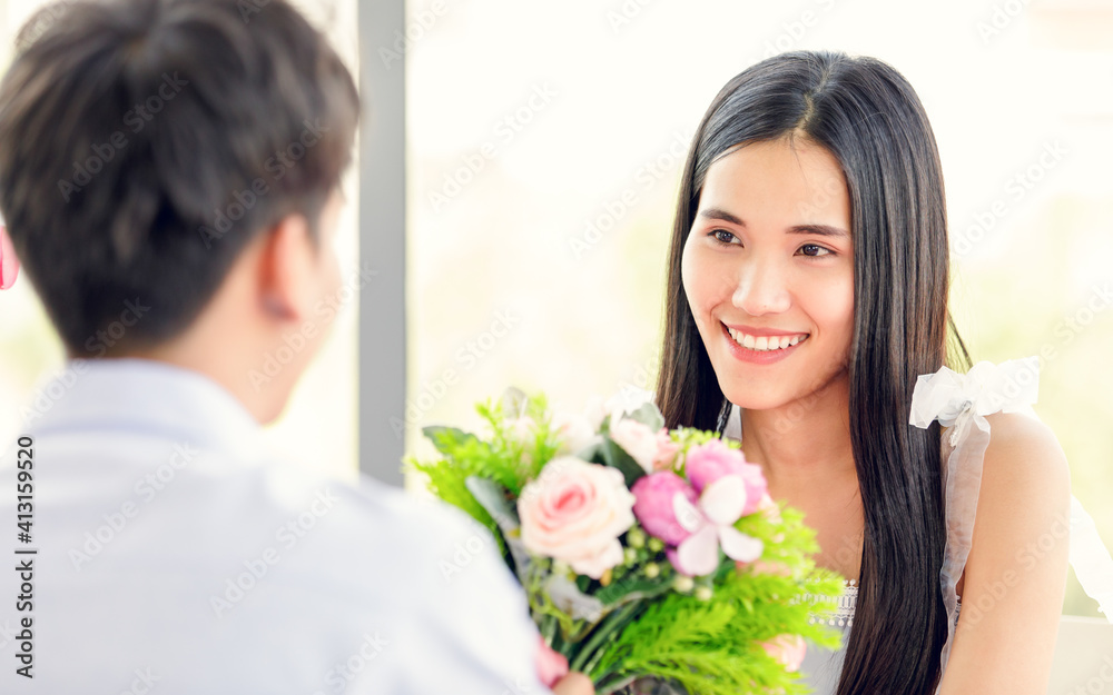 A young and cute beautiful Asian woman and her boyfriend talking with love and happiness. There is colorful bouquet between them. Love and valentine concept