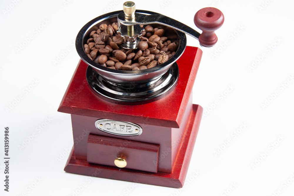 a dark red coffee grinder and coffee beans on white background