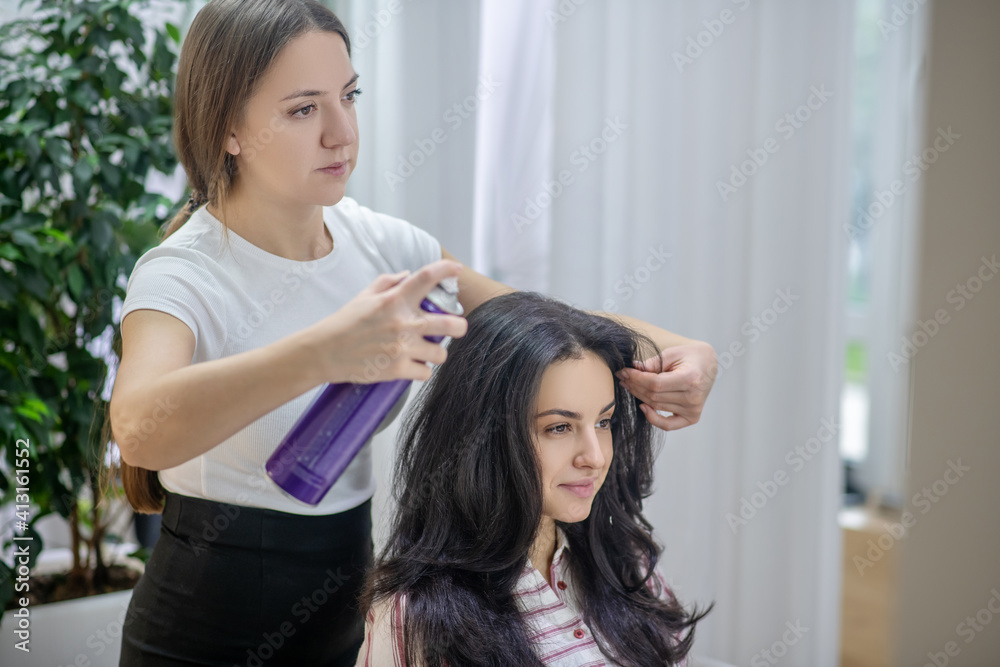 Naklejka premium Young long-haired woman making hairstyling in a hair salon