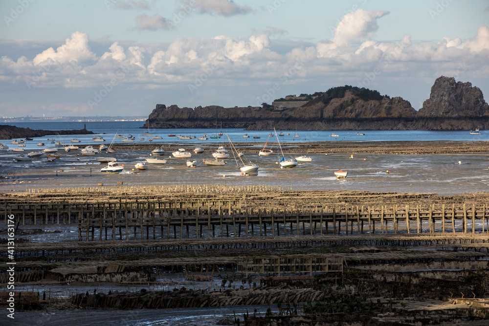 Boats on dry land at the beach at low tide in Cancale famous oysters production town, Brittany, France,