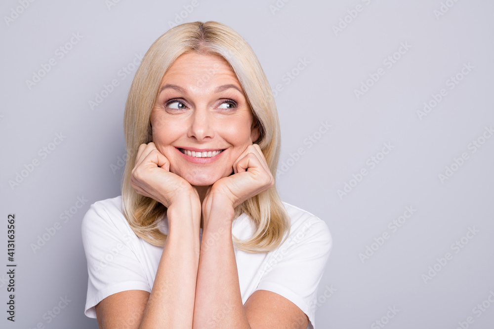 Photo of inspired old woman fists cheeks look empty space wear white t-shirt isolated grey color background Photo of inspired old woman fists cheeks look empty space wear white t-shirt isolated grey color background