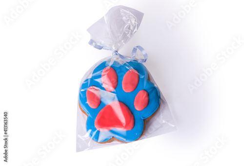 Ginderbread prepared in a shape of a dog paw covered with blue and red icing.