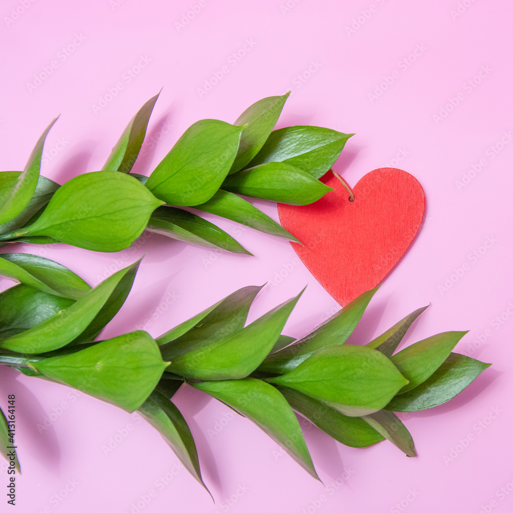 two bright green branches on a pink background and a wooden red heart 1х1