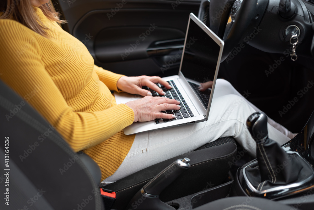 Businesswoman using her laptop in car Businesswoman using her laptop in car