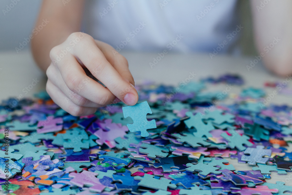 Caucasian girl collects puzzles on the table. Caucasian girl collects puzzles on the table.