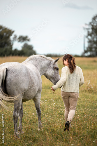 Young woman rider and her beautiful white horse, ooutdoors scene in countryside