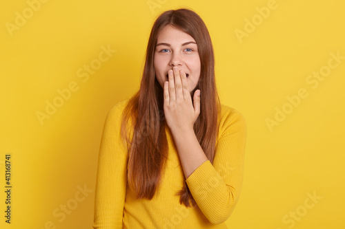 European surprised shocked astonished amazed girl covering mouth with hand, hearing unbelievable news, young beautiful woman on yellow background., emotional lady in casual attire.