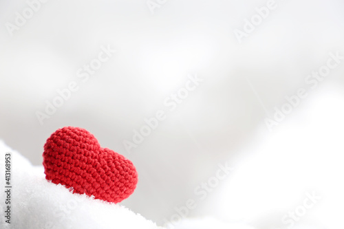 Love heart in the snow  background for Valentine s day card with blurred copy space. Red knitted symbol of romantic love