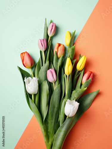 Overhead view of bouquet of colorful tulips on dual tone orange and mint background. Minimal floral spring concept. Valentine's or 8th March background. Flat lay, top view. photo