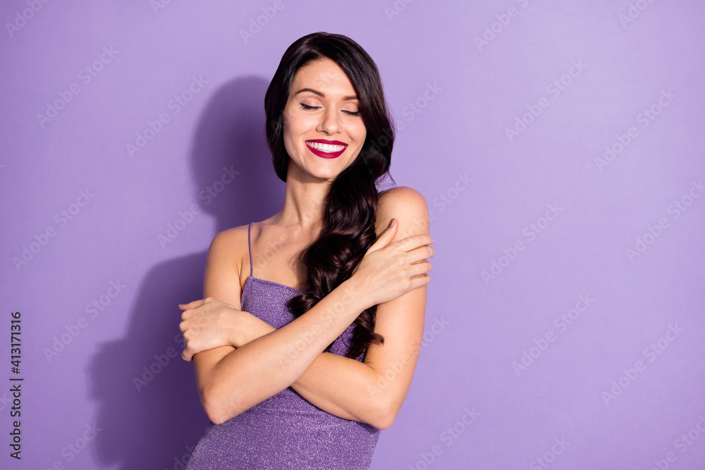 Photo of young cheerful girl happy positive smile enjoy hug herself dream dreamy isolated over purple color background Photo of young cheerful girl happy positive smile enjoy hug herself dream dreamy isolated over purple color background
