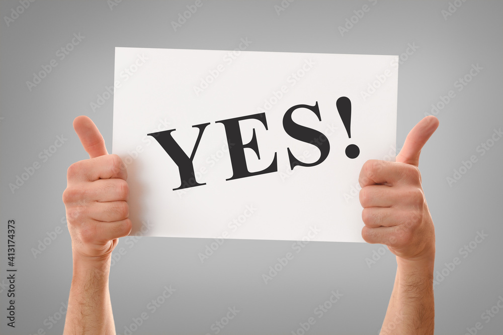 Two hands holding white sheet with yes message isolated background Two hands holding white sheet with yes message isolated background