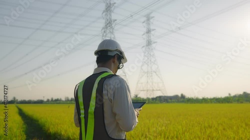 Electrical engineer worker in helmet  working near tower with electricity. business energy technology industry concept. electrician studying reading documents on a tablet
