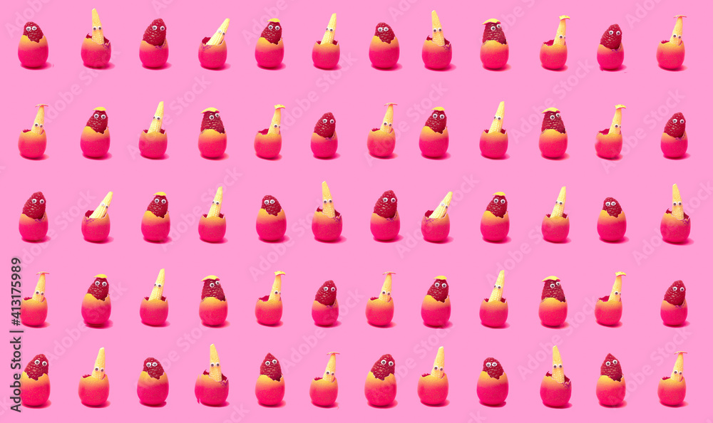 Pattern created of raspberry and baby corns with wiggle eyes in pink egg shell with egg shells on the bottom. Pink background. Pattern created of raspberry and baby corns with wiggle eyes in pink egg shell with egg shells on the bottom. Pink background.