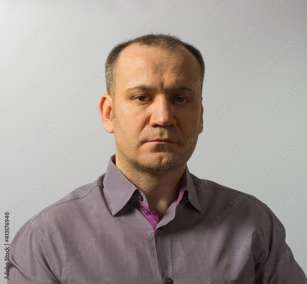 Obraz premium confident slightly unshaven man in gray shirt on gray background.