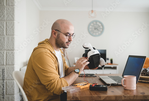 engineer man fixes his virtual real glasses at home. Young man with glasses fixing vr glasses.