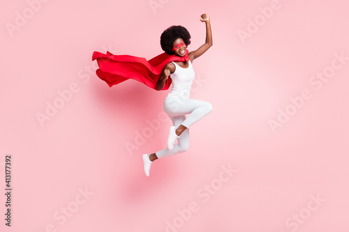 Full length body size view of active cheery girl jumping rejoicing wearing hero costume isolated on pink pastel color background photo