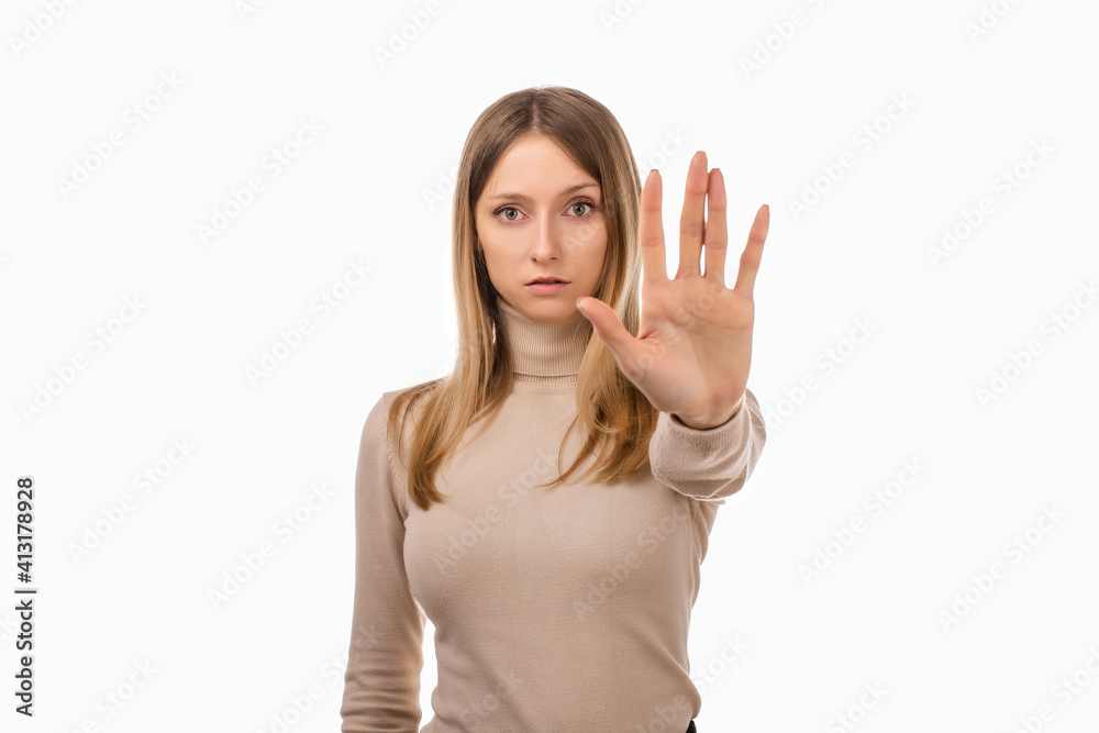 Serious blond girl keeps palm forward at camera, makes forbid sign, restricts or warns, extends arm in stop sign Serious blond girl keeps palm forward at camera, makes forbid sign, restricts or warns, extends arm in stop sign