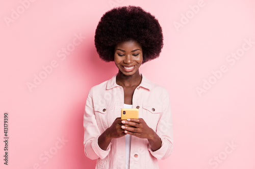 Portrait of pretty focused cheerful wavy-haired girl using device texting isolated over pink pastel color background