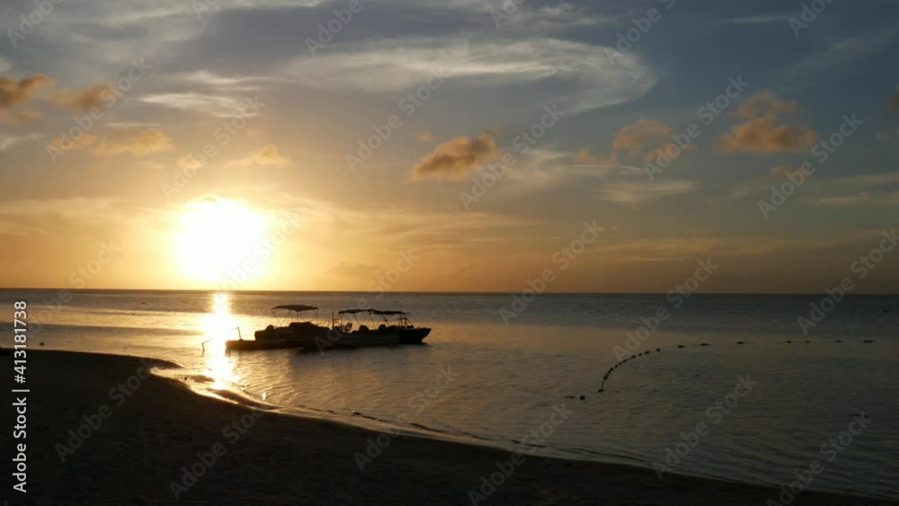 Golden reflections of the sunset at the beach, with a boat docked Golden reflections of the sunset at the beach, with a boat docked