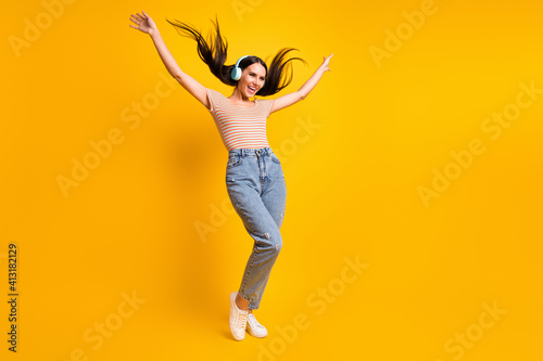 Full length body size photo of dancing moving at disco girl earphones laughing looking empty space isolated on vivid yellow color background