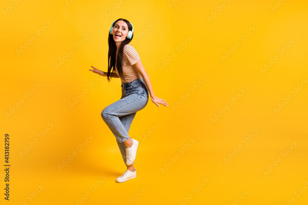 Full length body size photo of dancing singing girl wearing headphones looking empty space isolated on vivid yellow color background