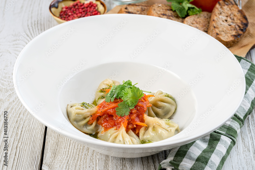 Cooked dumplings with spinach in a white plate shot from the side