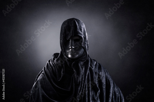 Scary figure with hooded cape in the dark