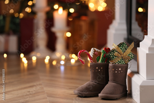 Boots filled with sweets and gift on floor in room, space for text. Saint Nicholas Day photo