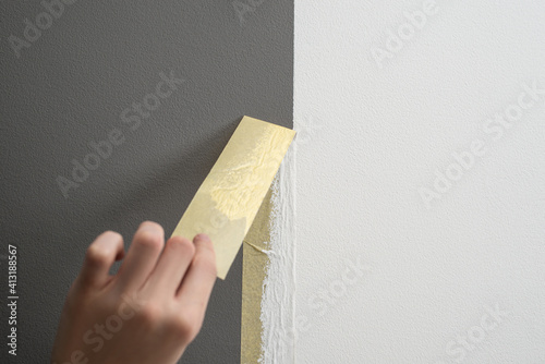 Hand taking off masking tape from the wall after painting